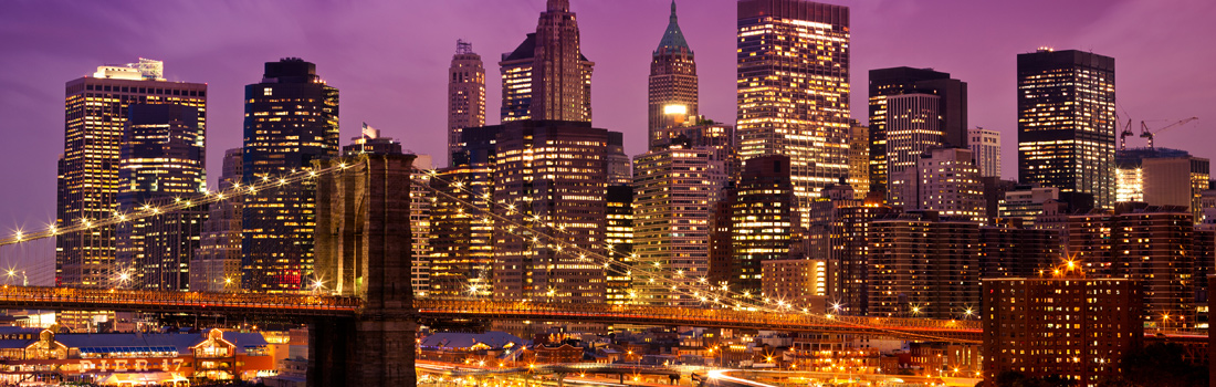 A city skyline with skyscrapers lit up at night.