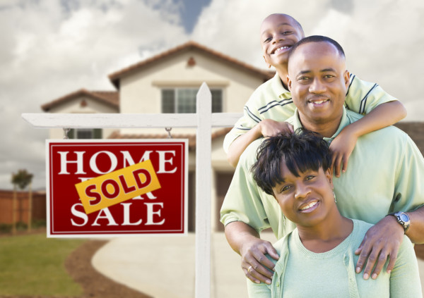 A family is standing in front of their home.