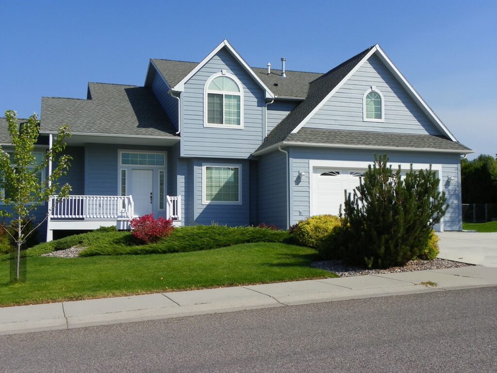 A house with a driveway and bushes in front of it.